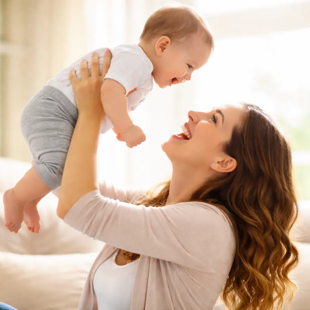 Mamma håller upp sin bebis och flirtar med honom. Bebisen har full tillit till sin mamma.